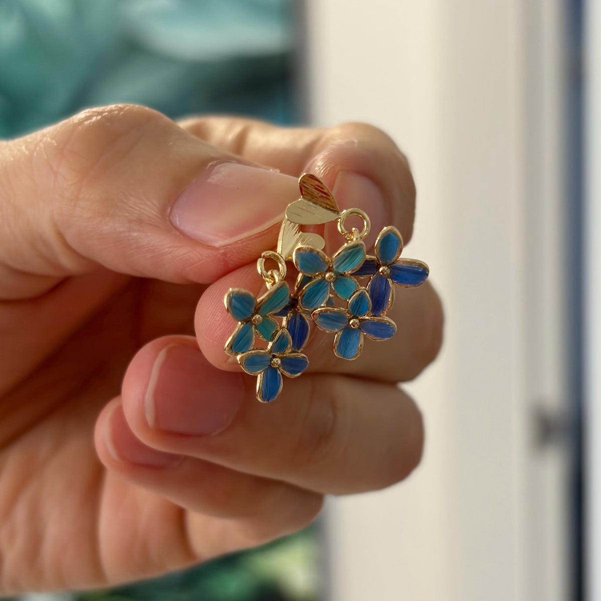 Hydrangea stud earrings held in the hand to show their size